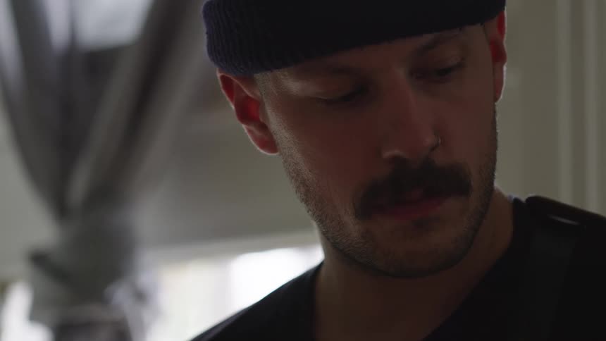 Close up portrait of a young man playing a musical instrument in a room during daytime