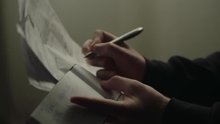 Hands hold notebook and pen while writing with blurred background