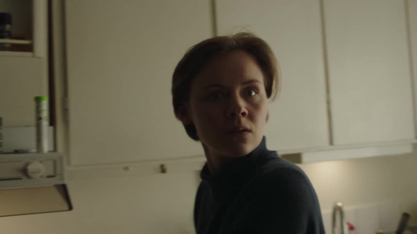 A young woman in the kitchen suddenly turns around at midday her face showing fear