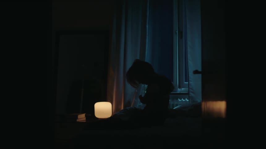 Woman taking off a blouse and lying in bed at night