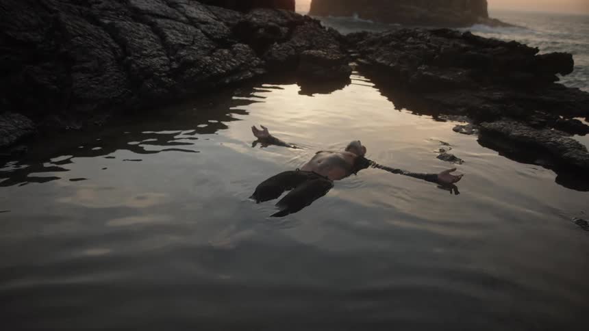 The man is laying in the water on his back