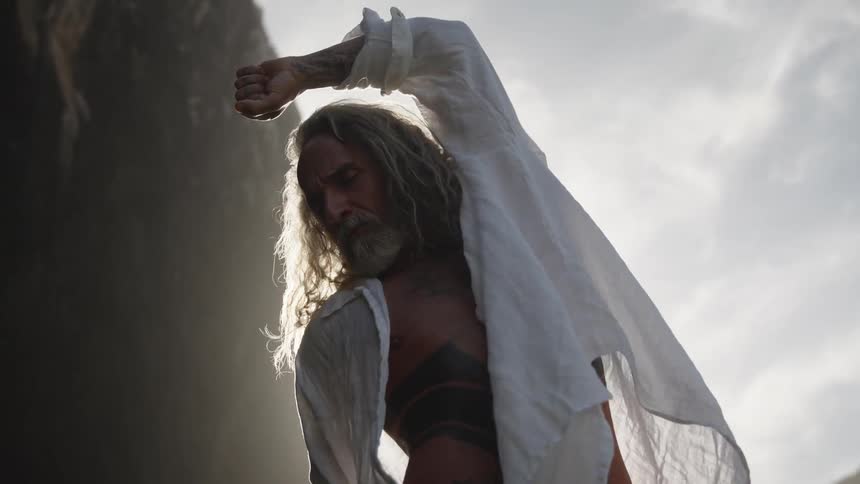 The man is stretching by the rocks