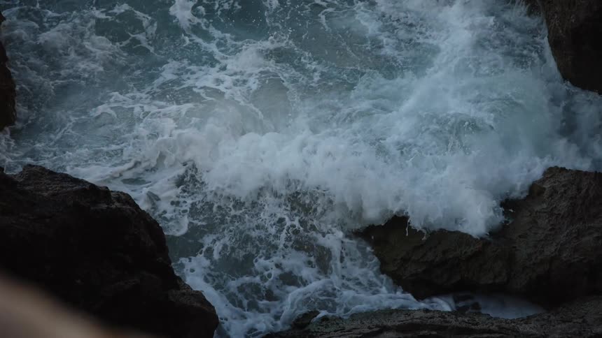 Aerial view of waves splashing against rocks along the coast