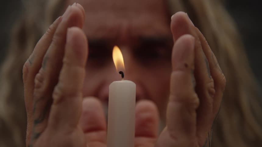 Man holding a candle flame reverently between his hands