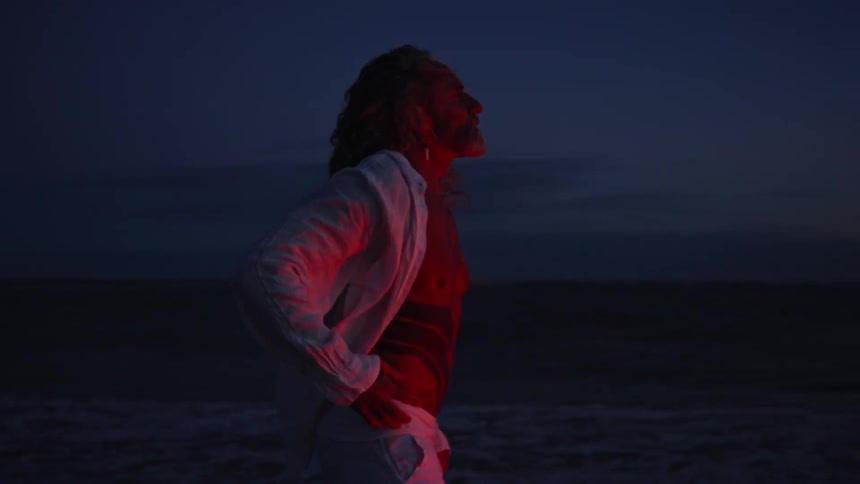 Man standing on a beach at night under red light