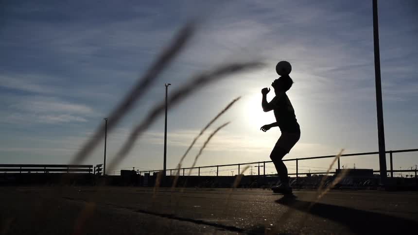 Man balancing a ball on his head at sunset