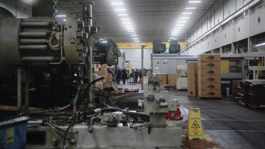 Workers pulling a cart with an engine on it through a large warehouse