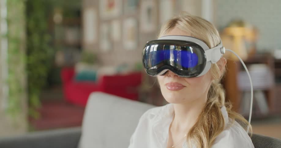 Young woman sitting on the couch wearing a virtual reality headset looking around