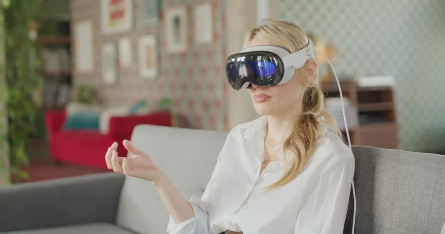 Woman wearing vr headset sitting on couch in bright room