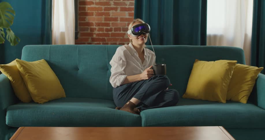 Woman wearing a vr headset exploring virtual reality on a couch in living room