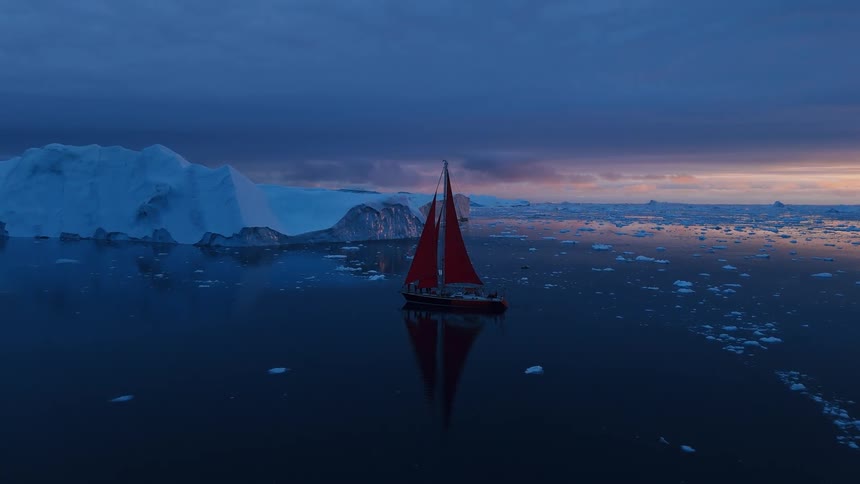 A vessel with a red sail moves across a dark water surface the boat is surrounded by pieces of floating ice a large wall of white and blue ice stands in the background and the sky is dark blue with a strip of orange near the horizon