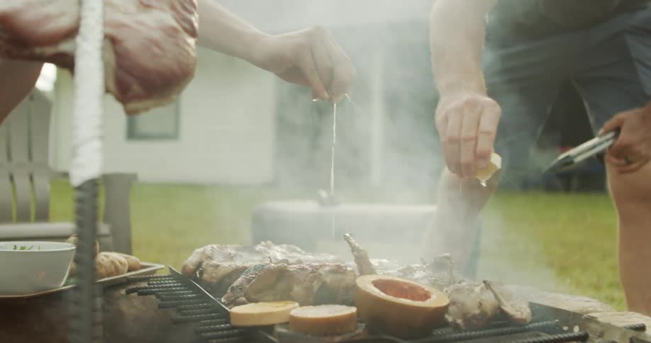 Two friends are grilling and roasting meat and veggies in the back yard
