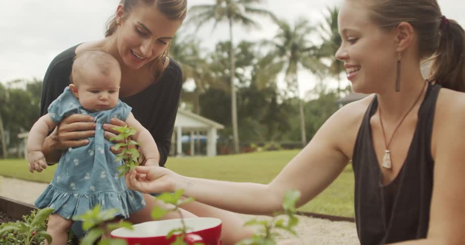 Two women spending time with a baby in an outdoor garden