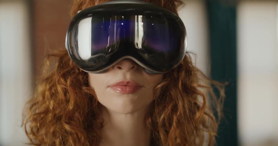 Teenage girl wearing a virtual reality headset turns her head and smiles as she moves her fingers