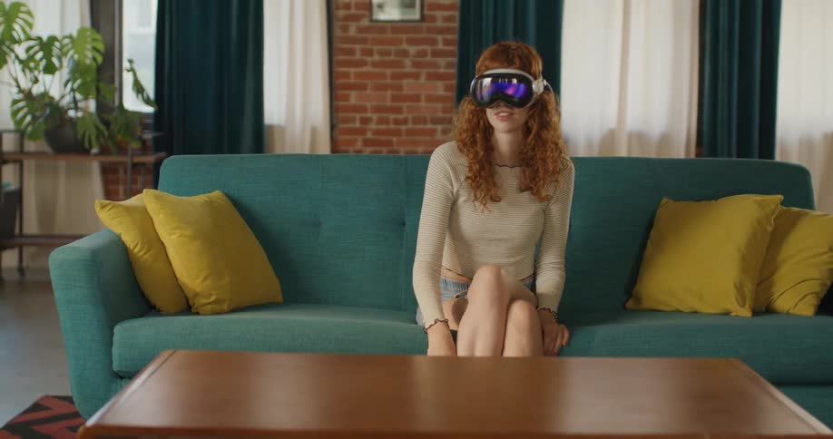 Woman wearing vr headset sitting on a sofa in a bright living room