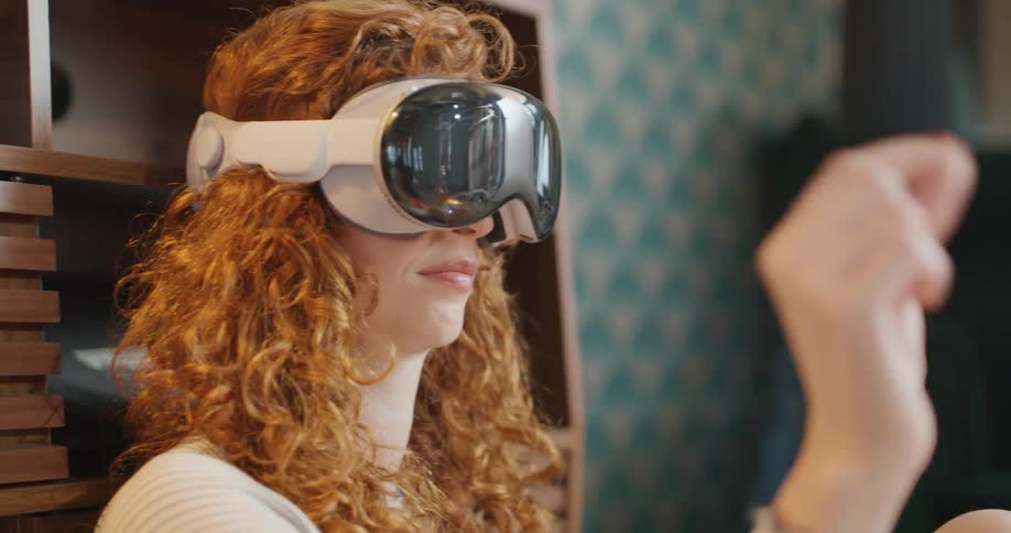 Teenage girl wearing a virtual reality headset holds up her hand and moves her fingers