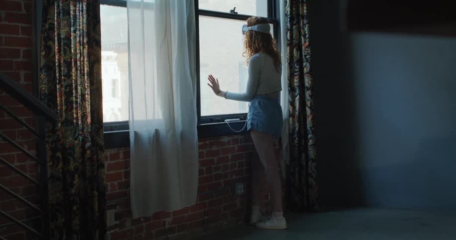 Woman wearing vr headset looking out a large window