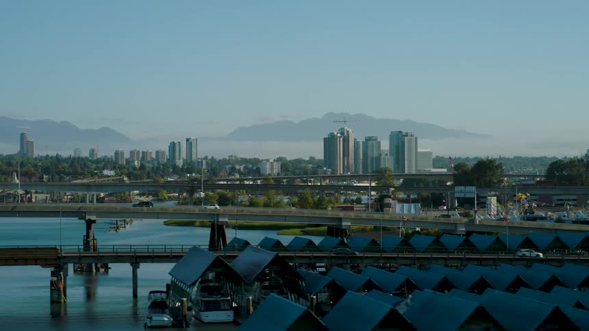 Aerial view of a city skyline with mountains and a harbor under blue sky