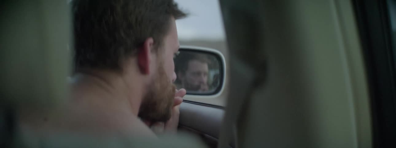 A man is sitting in a car looking out the window