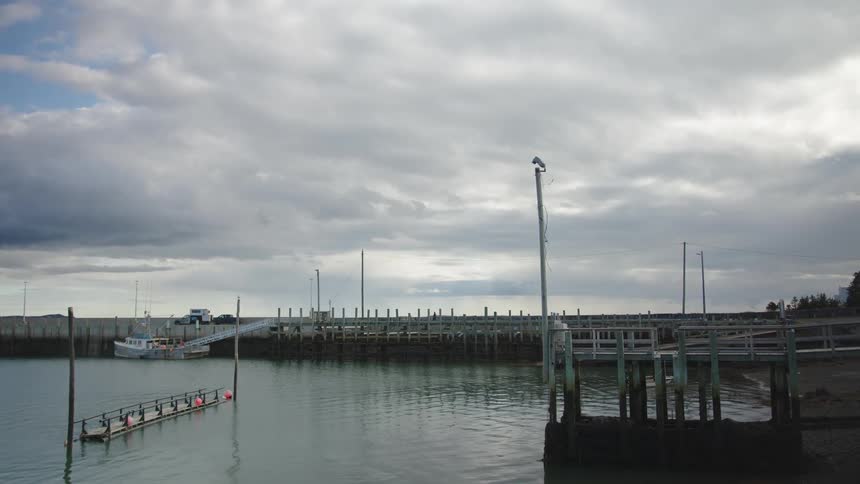 People move on a pier under an partially overcast sky