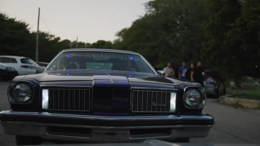 Men watch the hydraulic car jump up and down