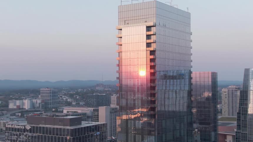 Facades on skyscrapers in a city reflect the setting sun