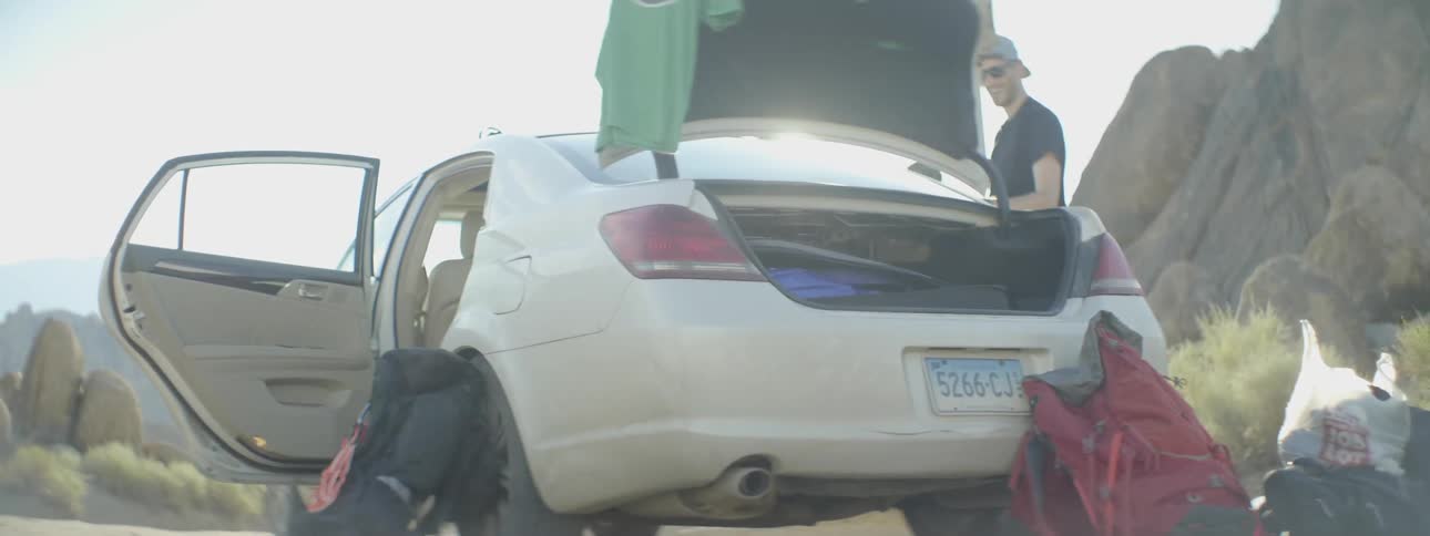 A car with its doors and trunk open with something leaning up against the side of it