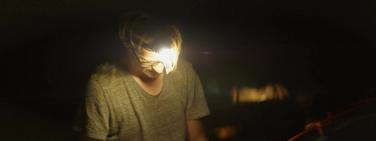 A man is setting up a tent at night