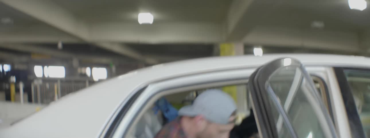 Man gets in the back of a white car and closes the door