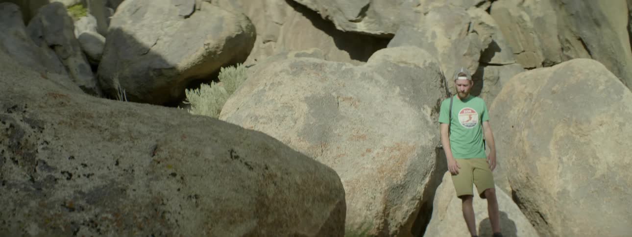 Man standing next to large boulders