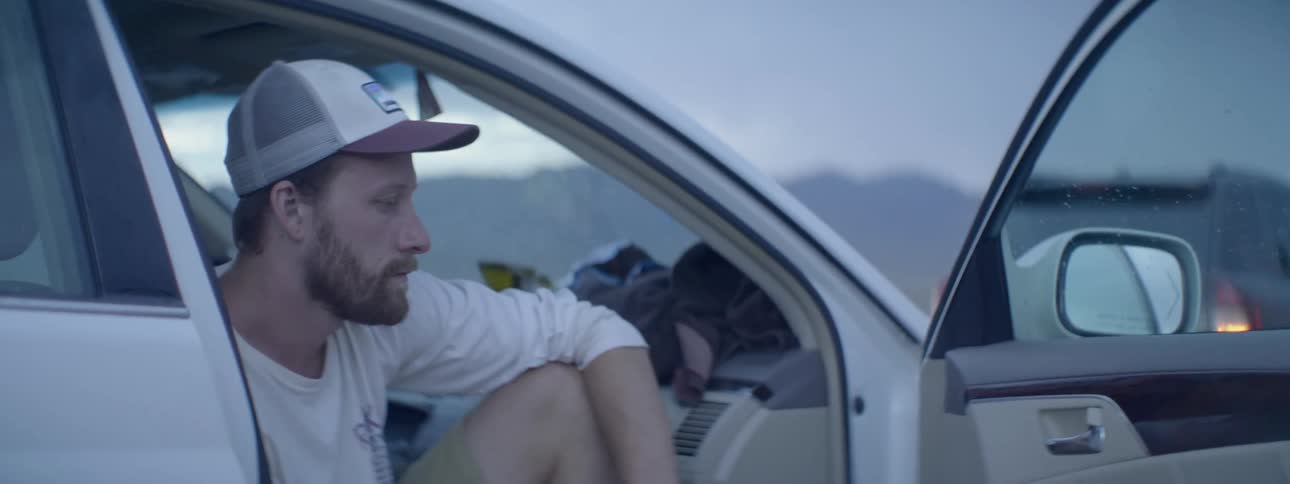 A man sits in a car looking around