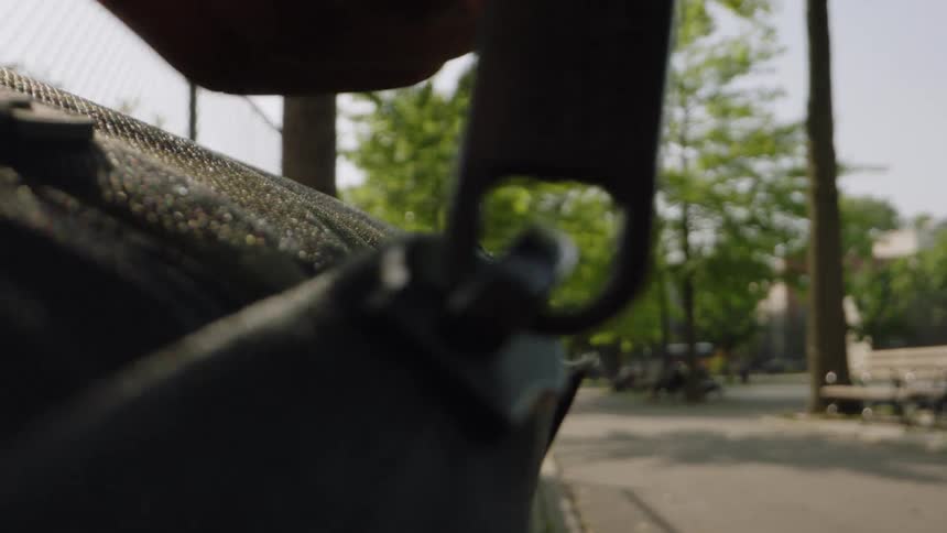 The man unzips his bag in the park