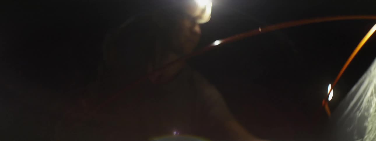 Man wearing headlight putting up tent at night