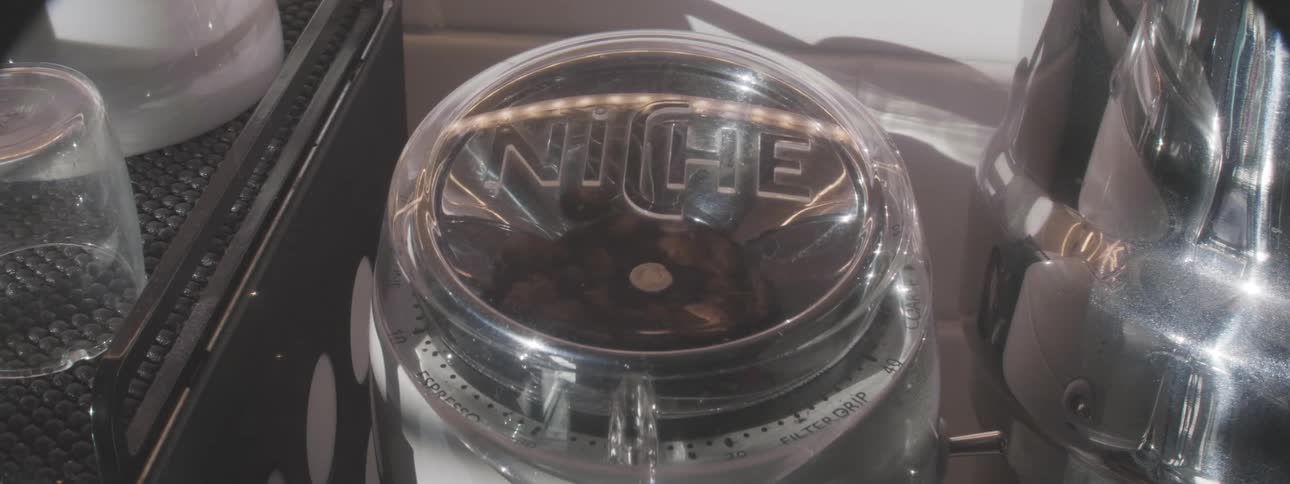 Closeup of a hand pouring coffee grounds into a grinder