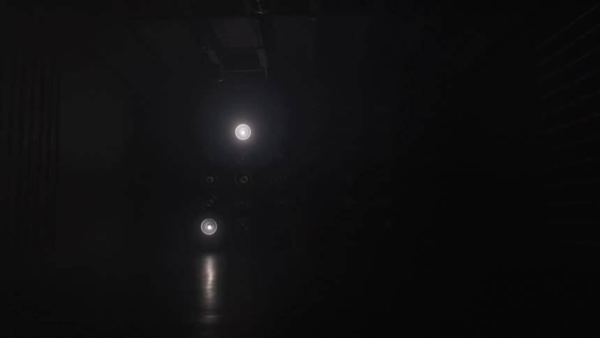A faint cluster of spotlights glimmer in a nearly black scene