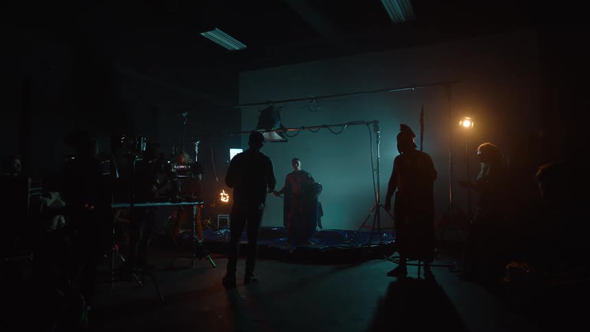 Director guides actors as the crew films in a dark studio