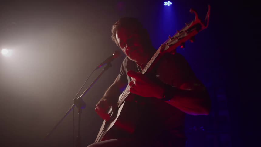 Musician plays an acoustic guitar as he performs on stage