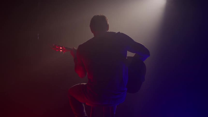 Musician plays the guitar on stage as he performs