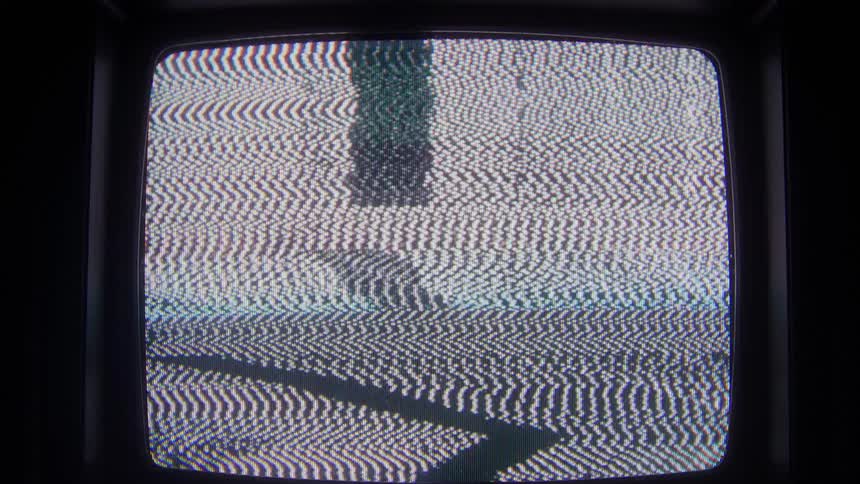 Television in a dark room with colored lines and static moving on the screen