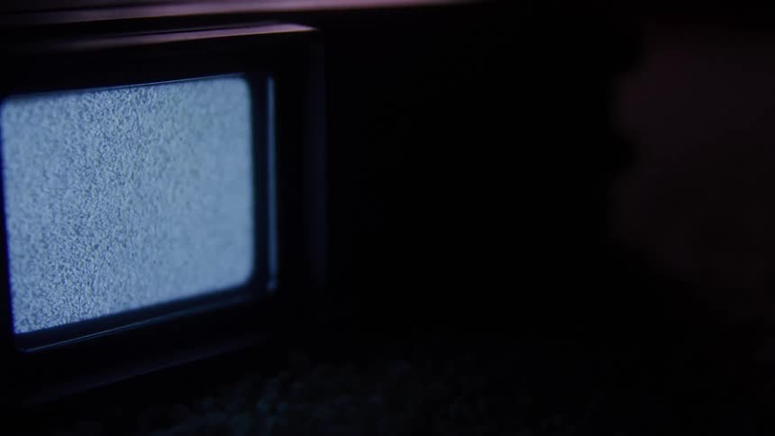Television in a dark room with static moving on the screen