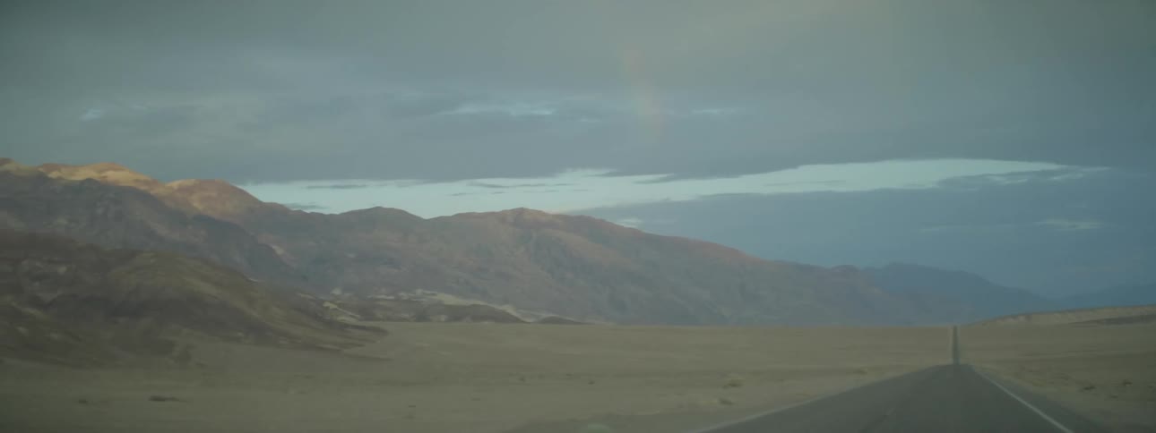 Heavy clouds are above this field and mountain range