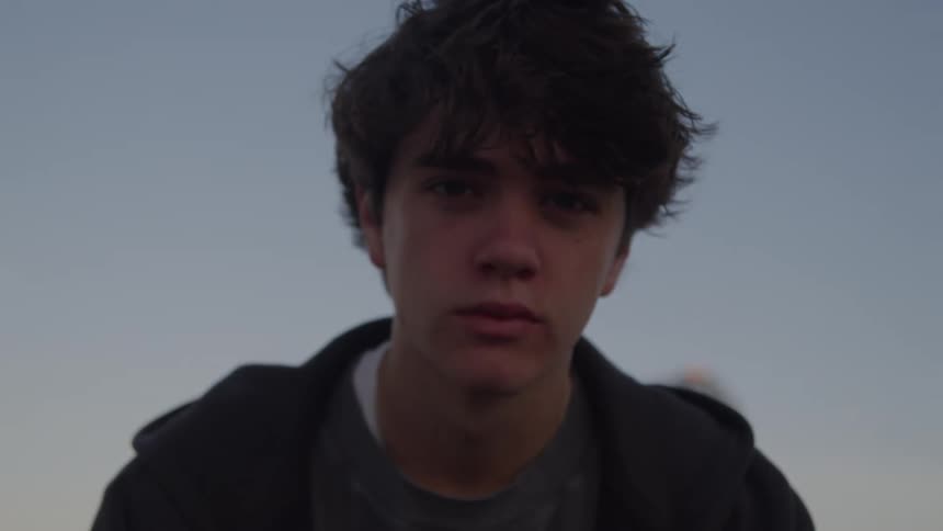 A teen boy is raising his head gazing in the distance