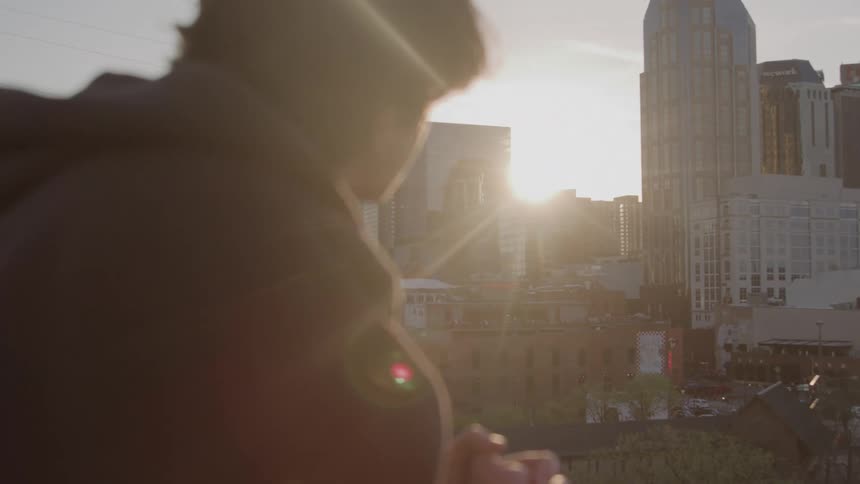 A person looks out over a city skyline at sunset