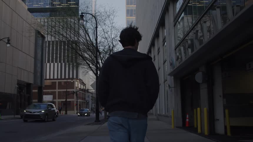 Male pedestrian walking along a sidewalk downtown passes the entrance to a parking garage