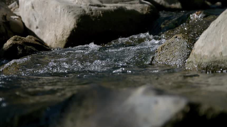 Slow motion of water in a stream flowing over several rocks