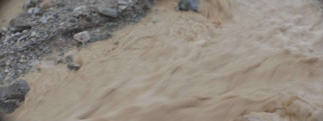 A small stream runs brown water over rocks