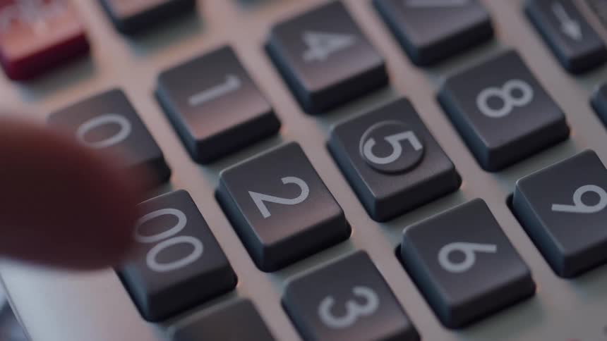 A finger presses several keys on the numeric keypad of a calculator