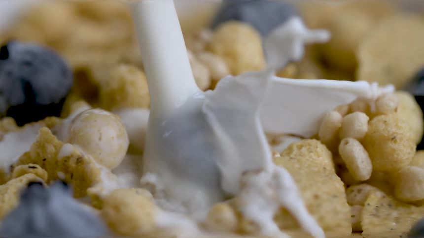 Close up pouring milk over cereal and blueberries