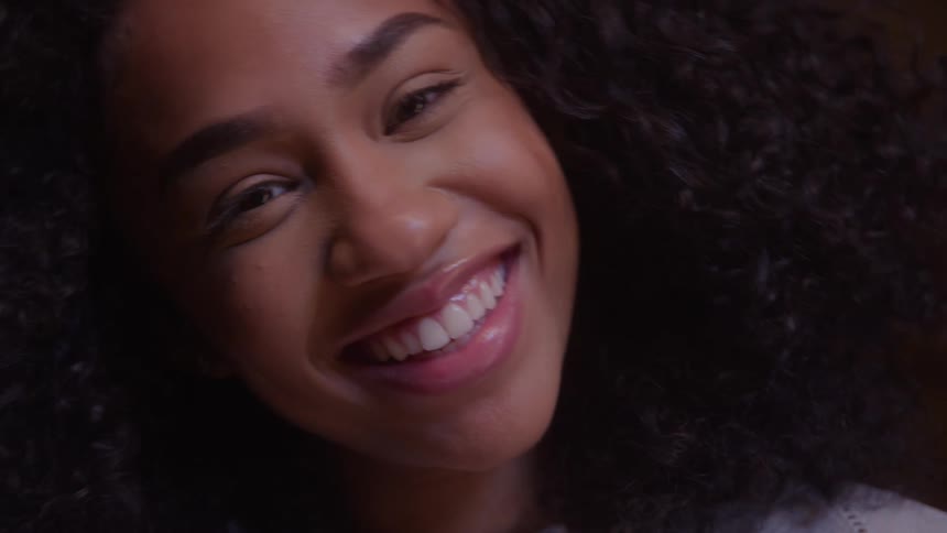 Close up portrait of a young black woman laughing while sitting indoors