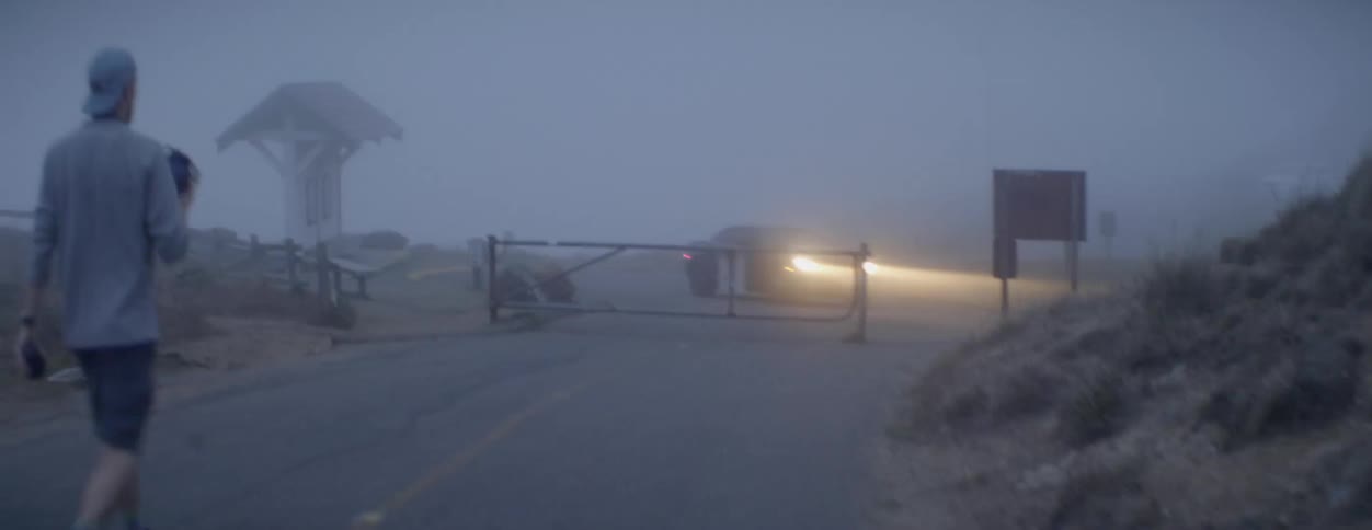 A man walks around a car turning by a gate